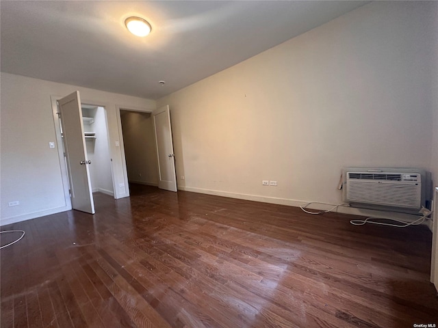 empty room with a wall mounted air conditioner and dark hardwood / wood-style floors