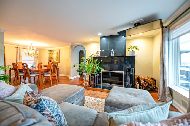 living room with a notable chandelier, dark parquet floors, ornamental molding, and a tile fireplace