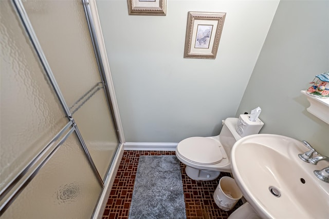 bathroom featuring toilet, a shower with door, and sink