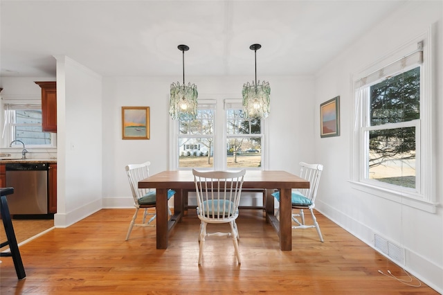 dining space with sink, light hardwood / wood-style flooring, and a healthy amount of sunlight