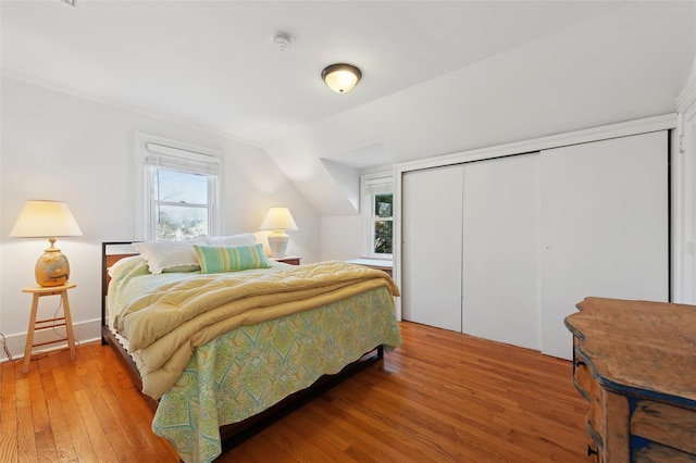 bedroom with a closet, vaulted ceiling, and hardwood / wood-style floors