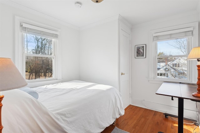 bedroom featuring ornamental molding, multiple windows, and wood-type flooring