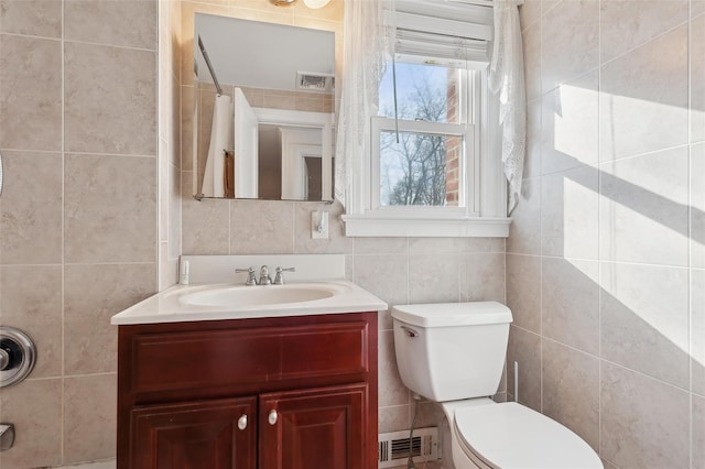 bathroom with vanity, toilet, and tile walls