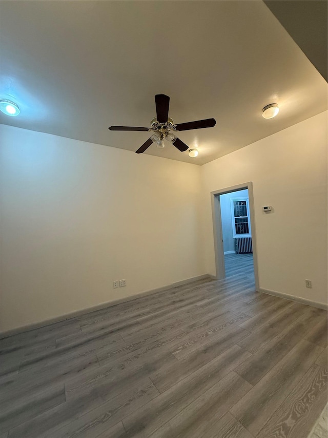 unfurnished room with ceiling fan, wood-type flooring, and radiator heating unit