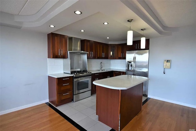 kitchen featuring pendant lighting, sink, decorative backsplash, stainless steel appliances, and wall chimney range hood