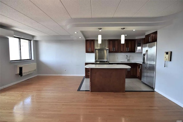 kitchen with dark brown cabinetry, sink, decorative light fixtures, a center island, and stainless steel fridge with ice dispenser