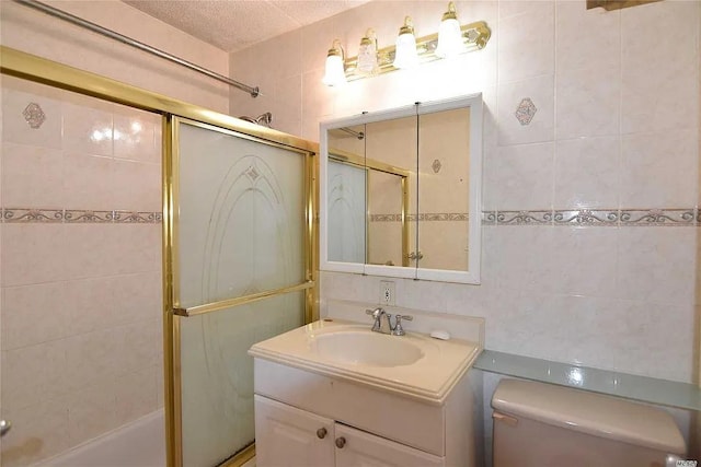 bathroom with vanity, toilet, tile walls, and a textured ceiling