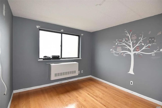 spare room with wood-type flooring and radiator