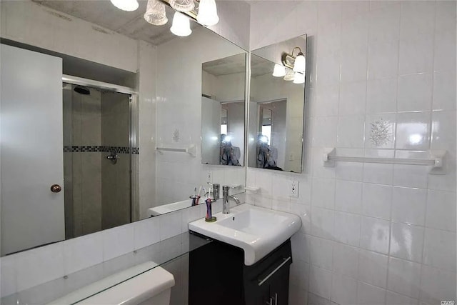 bathroom featuring vanity, tile walls, and a shower with shower door