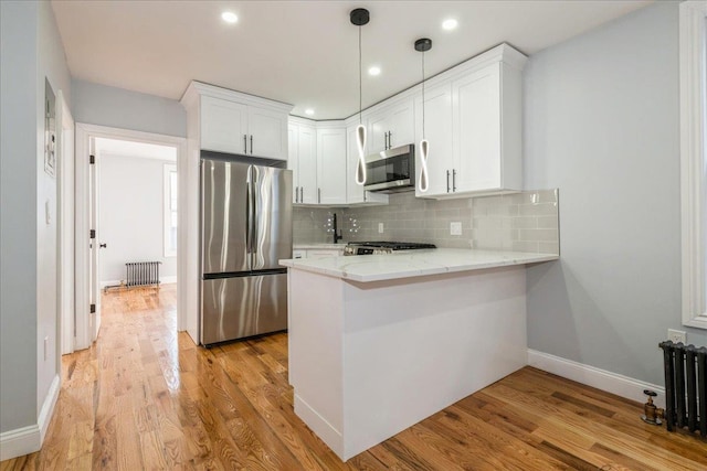 kitchen with light stone countertops, tasteful backsplash, white cabinets, kitchen peninsula, and stainless steel appliances