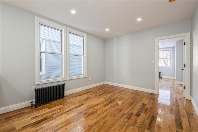 empty room featuring radiator and light hardwood / wood-style flooring