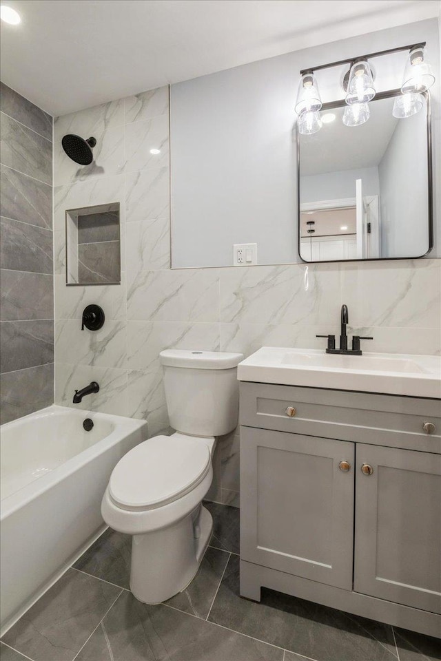 full bathroom with tiled shower / bath combo, toilet, vanity, and tile walls