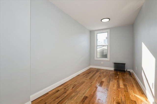 spare room featuring radiator and light hardwood / wood-style floors