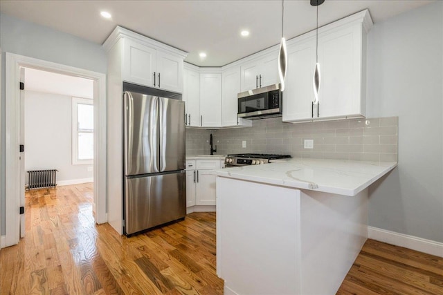 kitchen featuring white cabinetry, decorative backsplash, pendant lighting, and stainless steel appliances