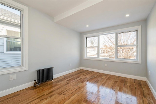 spare room featuring light wood-type flooring and radiator