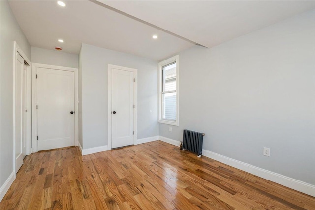 unfurnished bedroom featuring radiator heating unit and light hardwood / wood-style floors