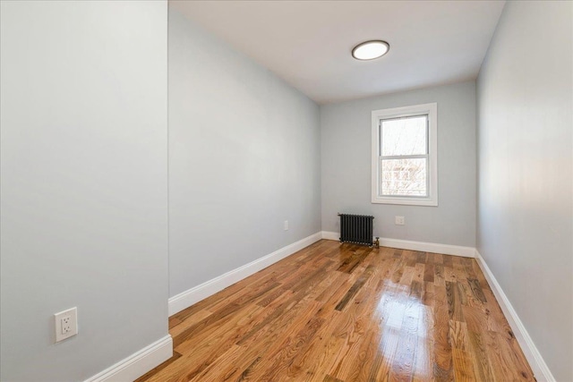 spare room featuring radiator heating unit and light hardwood / wood-style floors