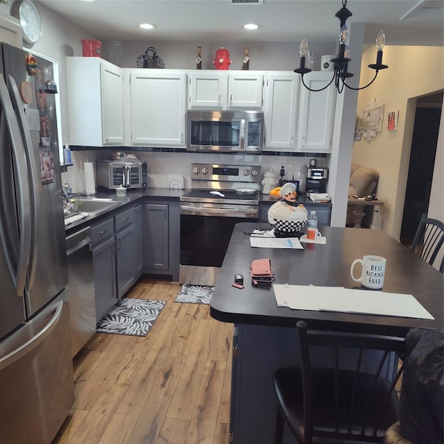 kitchen with light hardwood / wood-style flooring, white cabinets, tasteful backsplash, gray cabinets, and stainless steel appliances