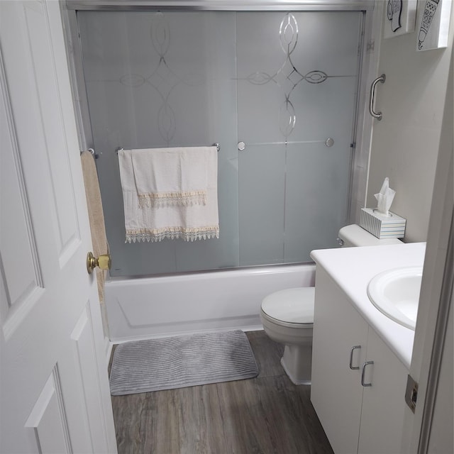 full bathroom featuring vanity, shower / bath combination with glass door, hardwood / wood-style floors, and toilet