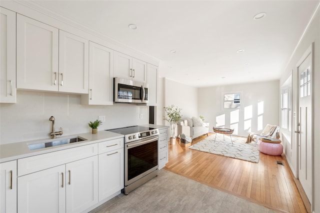 kitchen featuring sink, light hardwood / wood-style floors, white cabinetry, and appliances with stainless steel finishes