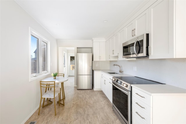 kitchen with white cabinets, light hardwood / wood-style floors, appliances with stainless steel finishes, and sink