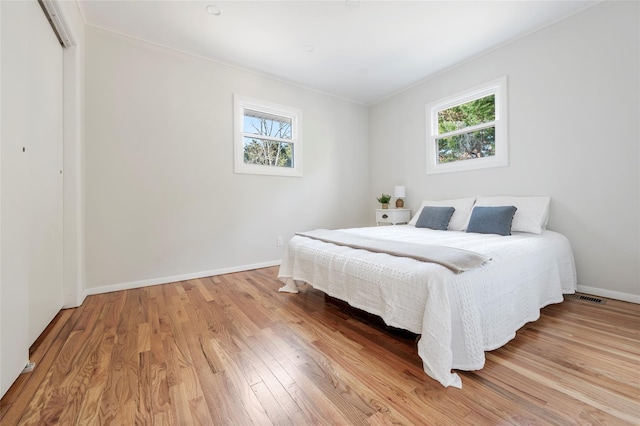 bedroom featuring a closet, light hardwood / wood-style floors, and multiple windows