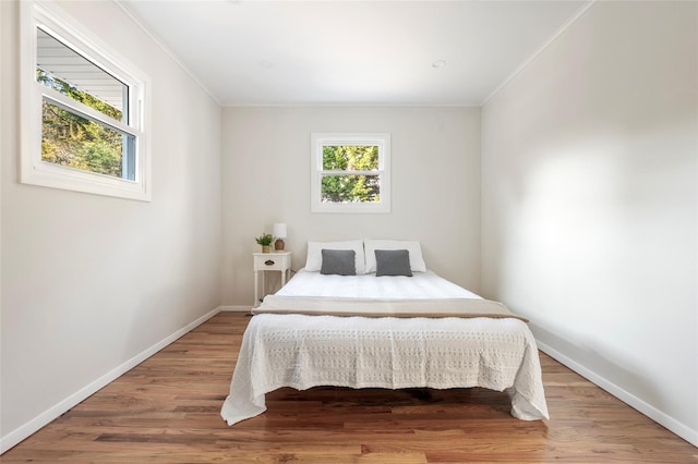 bedroom with ornamental molding and wood-type flooring