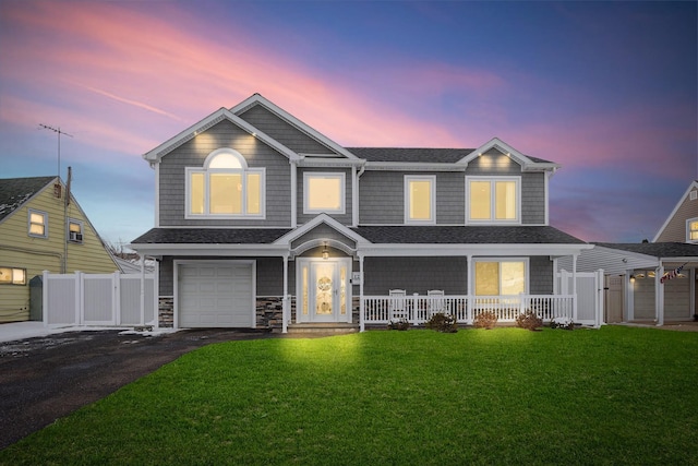 view of front of house featuring a garage, a lawn, and covered porch