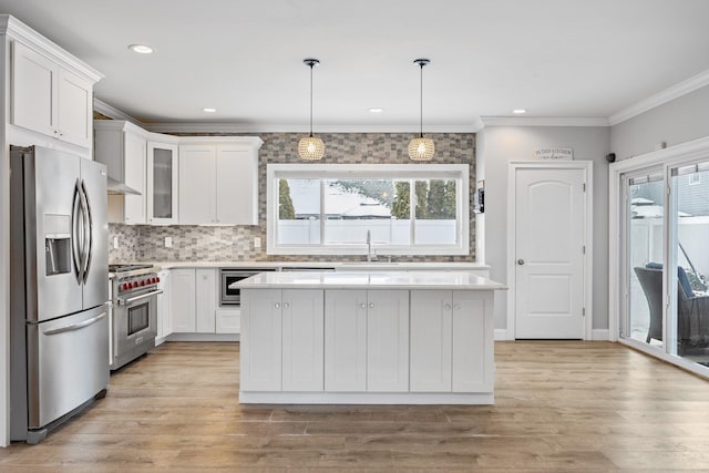 kitchen with a center island, white cabinetry, decorative light fixtures, ornamental molding, and stainless steel appliances