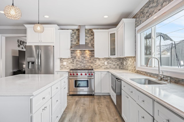 kitchen with sink, white cabinets, decorative light fixtures, stainless steel appliances, and wall chimney exhaust hood