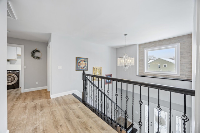 hall with light hardwood / wood-style flooring, a notable chandelier, and washer / clothes dryer