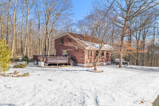 snow covered back of property featuring a wooden deck