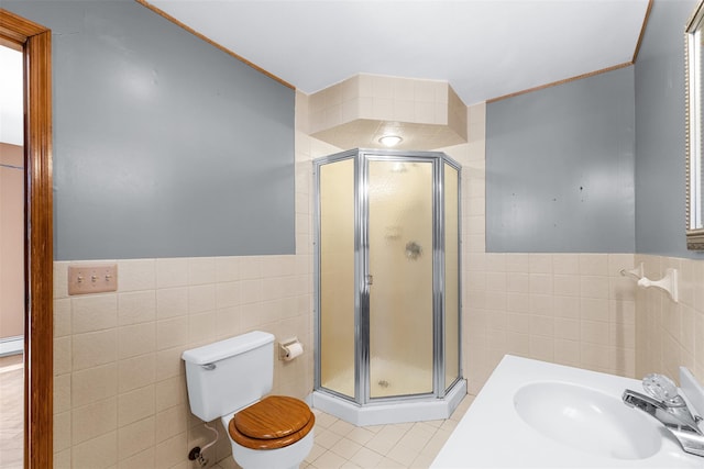 bathroom featuring sink, toilet, a shower with shower door, and tile walls