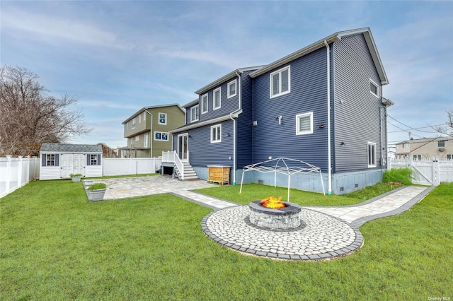 rear view of property with an outdoor fire pit, a patio area, a yard, and a storage unit