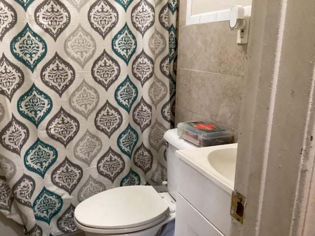 bathroom with vanity, toilet, and tile walls