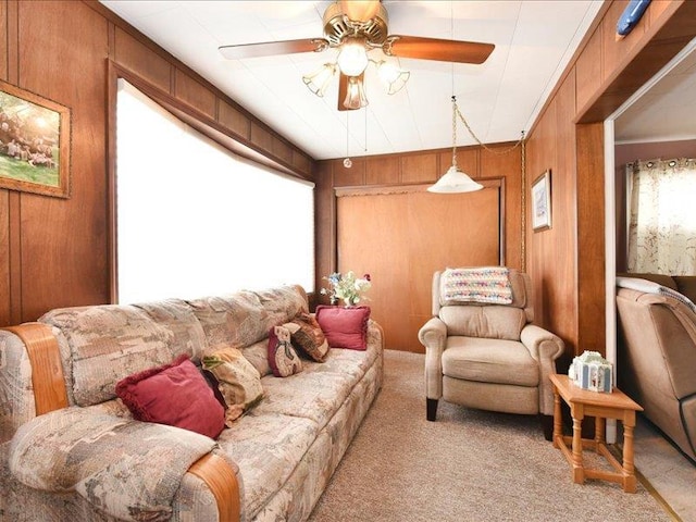 living room with ceiling fan, wood walls, and light carpet