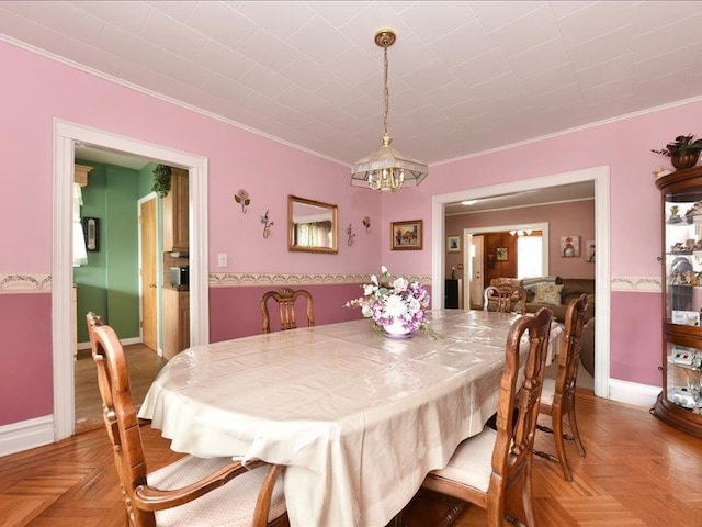 dining area featuring crown molding, parquet floors, and a notable chandelier