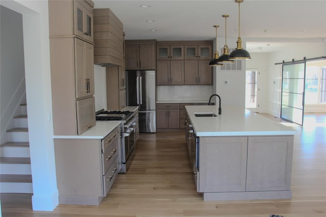 kitchen featuring pendant lighting, sink, backsplash, a kitchen island with sink, and stainless steel appliances