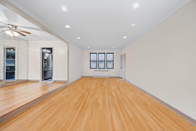 unfurnished living room with ornamental molding, radiator heating unit, ceiling fan, and light wood-type flooring