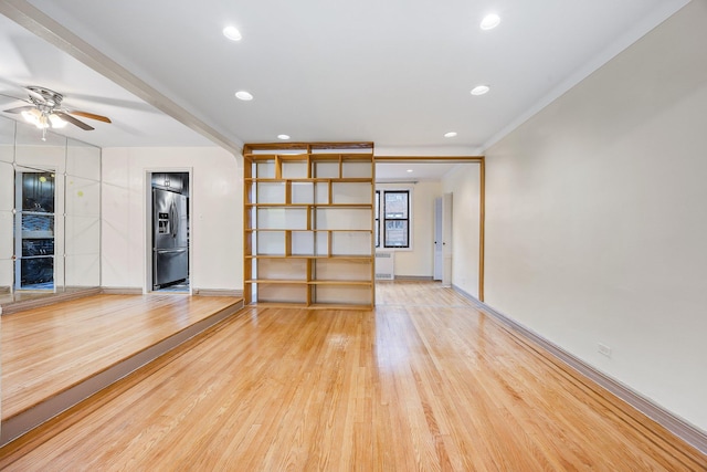 unfurnished living room with crown molding, radiator heating unit, ceiling fan, and light wood-type flooring