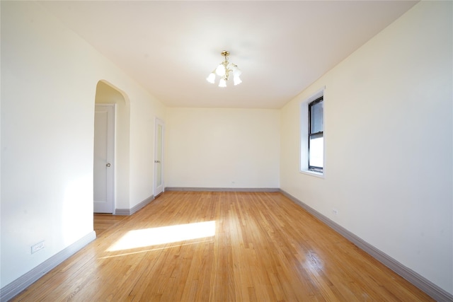 empty room featuring an inviting chandelier and light wood-type flooring