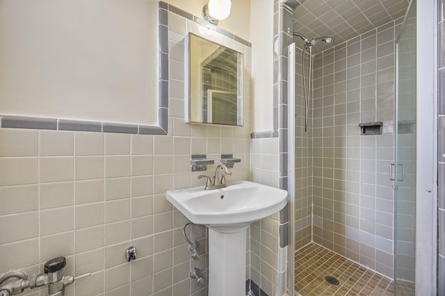 bathroom with sink, tile walls, and a shower with shower door