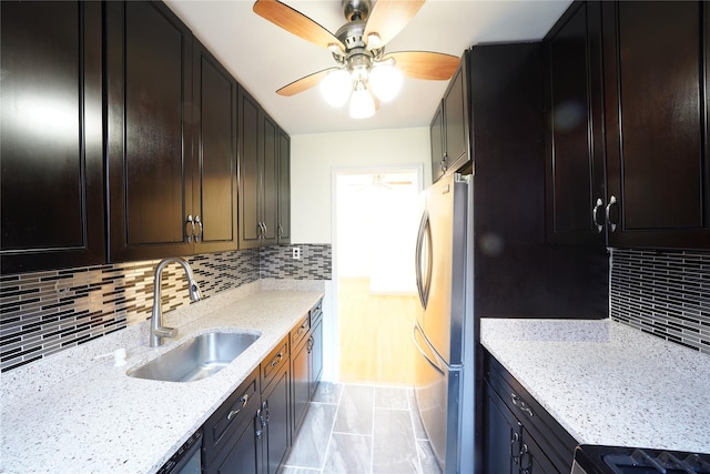 kitchen featuring sink, backsplash, stainless steel fridge, stove, and light stone counters