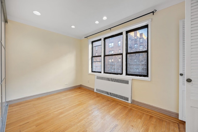 unfurnished room featuring radiator and light hardwood / wood-style floors