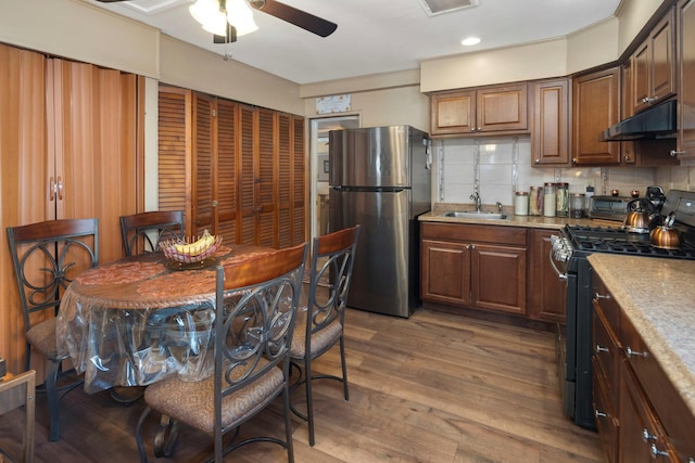 kitchen with hardwood / wood-style floors, tasteful backsplash, sink, ceiling fan, and stainless steel appliances