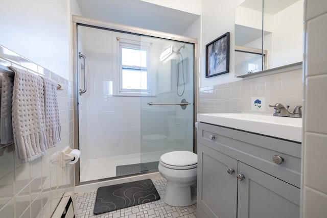 bathroom with tile patterned floors, a shower with door, vanity, tile walls, and toilet