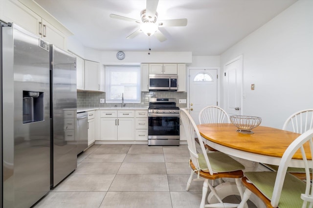 kitchen featuring light tile patterned floors, white cabinets, sink, backsplash, and stainless steel appliances