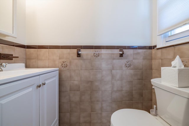 bathroom with vanity, toilet, and tile walls