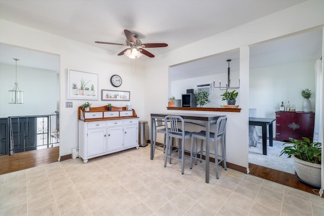 kitchen with white cabinets, ceiling fan with notable chandelier, hanging light fixtures, and a breakfast bar