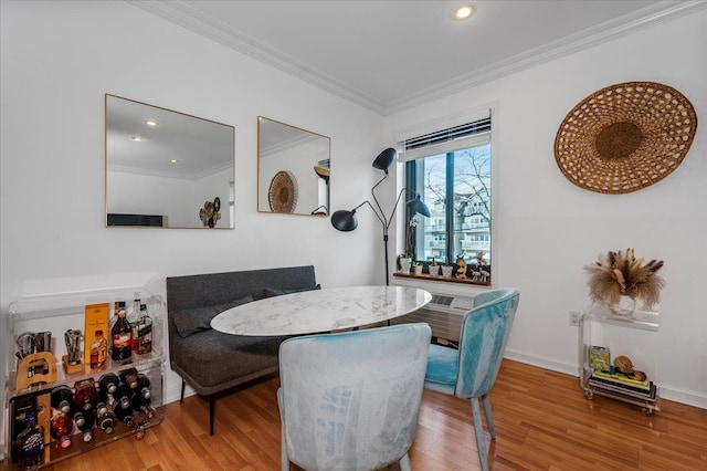 dining room featuring wood-type flooring, ornamental molding, and breakfast area